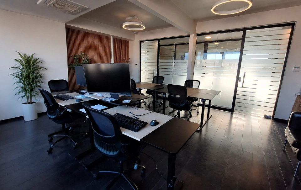 Moderno opremljeni privatni ured A1 u coworking prostoru, s radnim stolovima za šest osoba, biljkom u kutu, i staklenim zidovima.